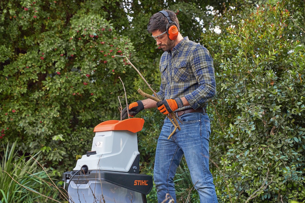 Muž v ochranných pomůckách drtí větve drtičem STIHL  