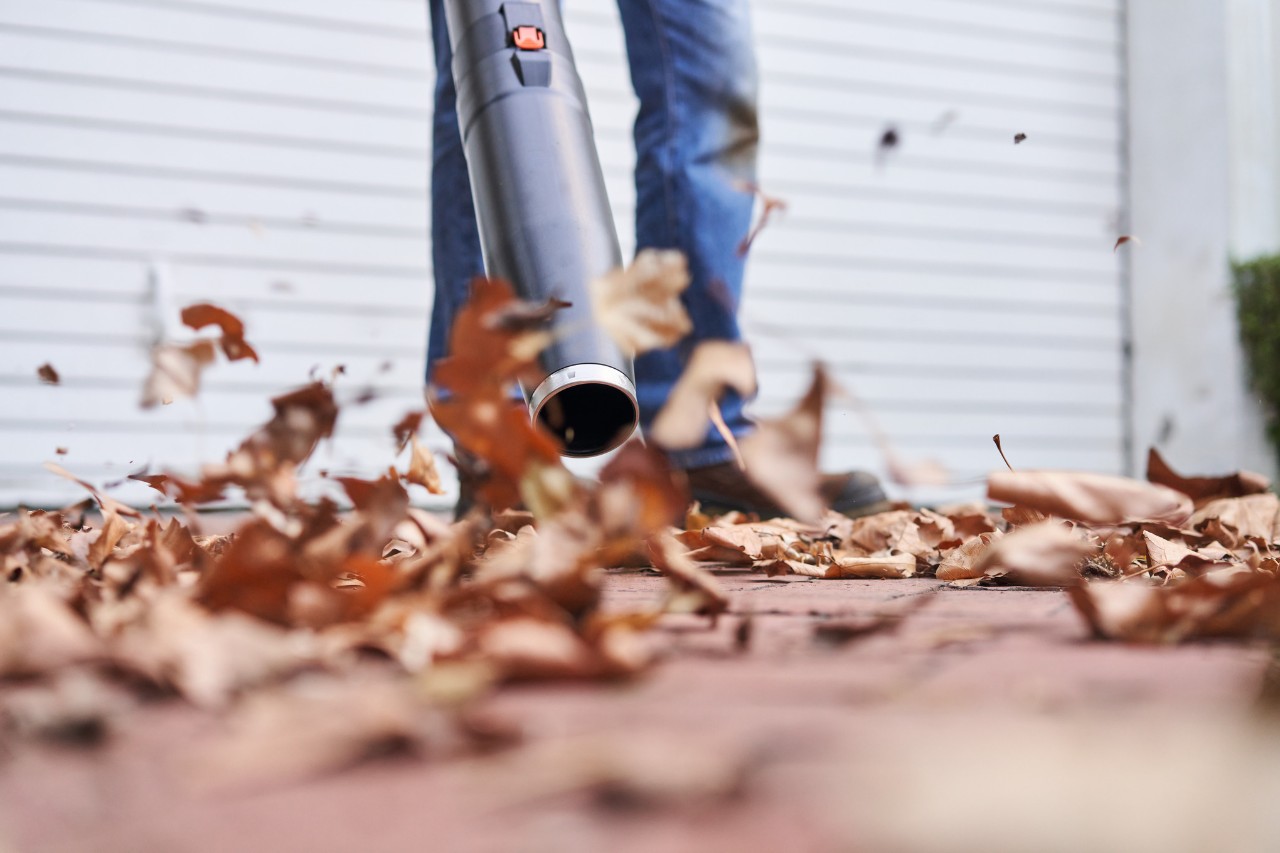 Detailní snímek fukaru, který víří listí před garáží