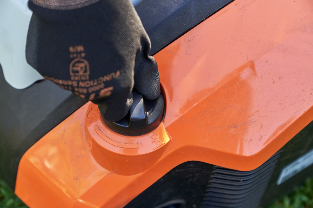 Detailní záběr: Ruka s pracovní rukavicí STIHL FUNCTION SENSOTOUCH otáčí otočnou rukojetí akumulátorového provzdušňovače trávníku STIHL RLA 240.