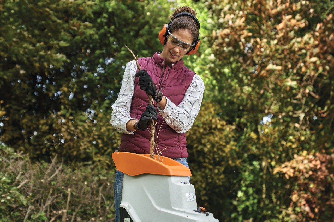 Žena v ochranném oděvu drtí větev elektrickým drtičem zahradního odpadu STIHL GHE 140 L