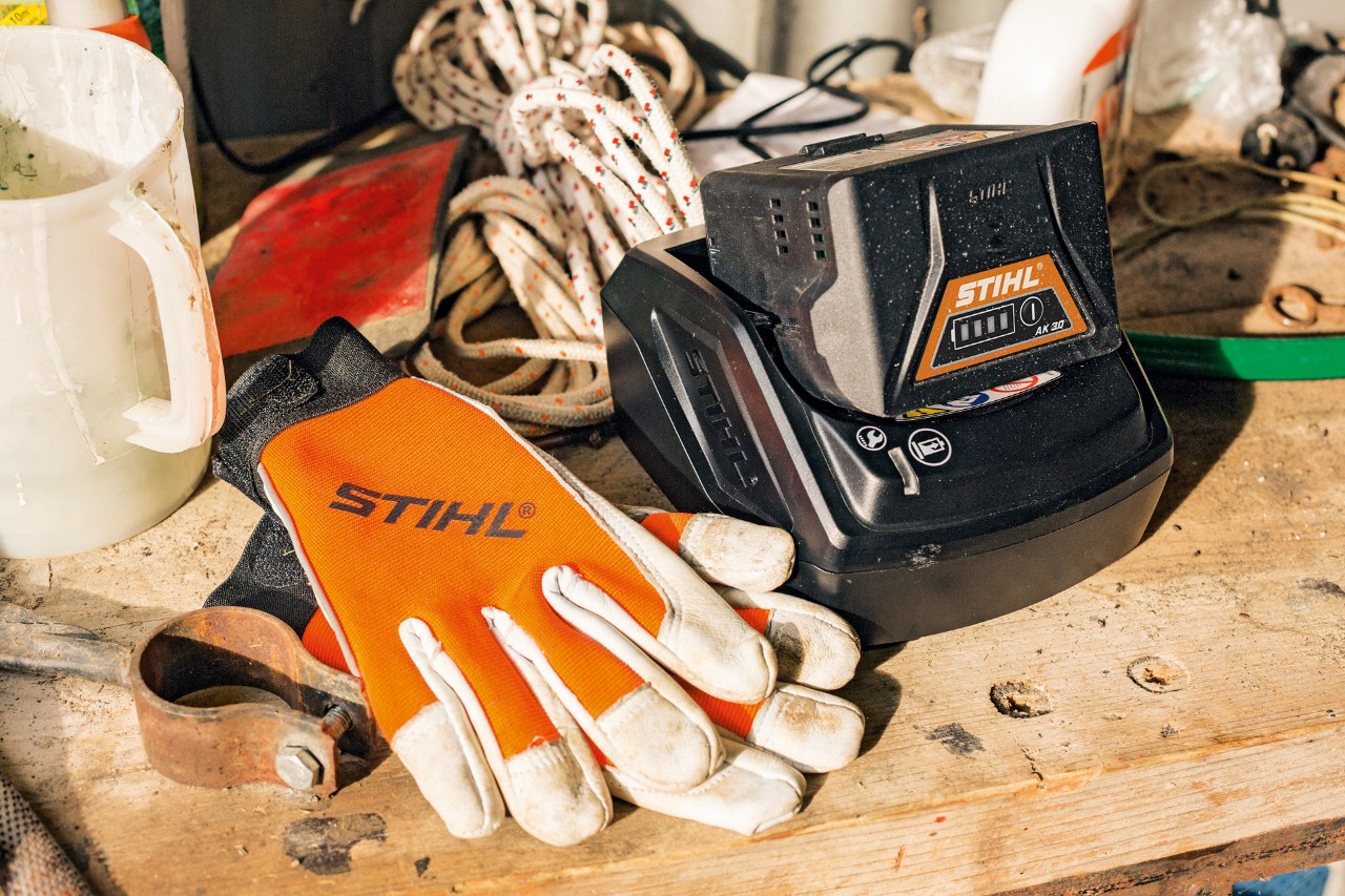 Nabíjení lithium-iontových akumulátorů řady AK vedle rukavic a pracovního nářadí STIHL