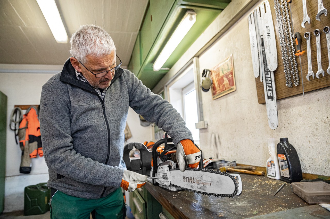 Muž napíná řetěz řetězové pily STIHL