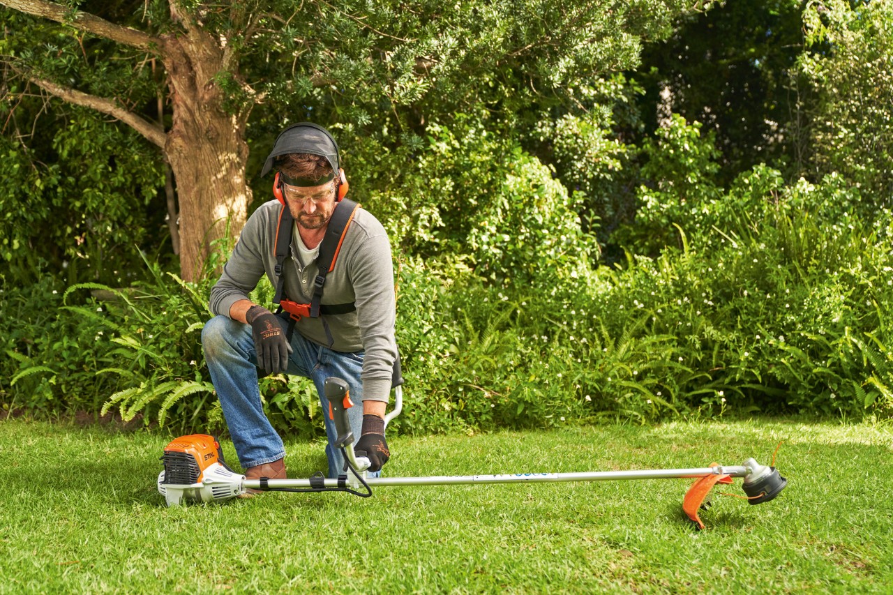 Muž pokládá benzinový křovinořez STIHL FS 91 na zem, aby ho nastartoval