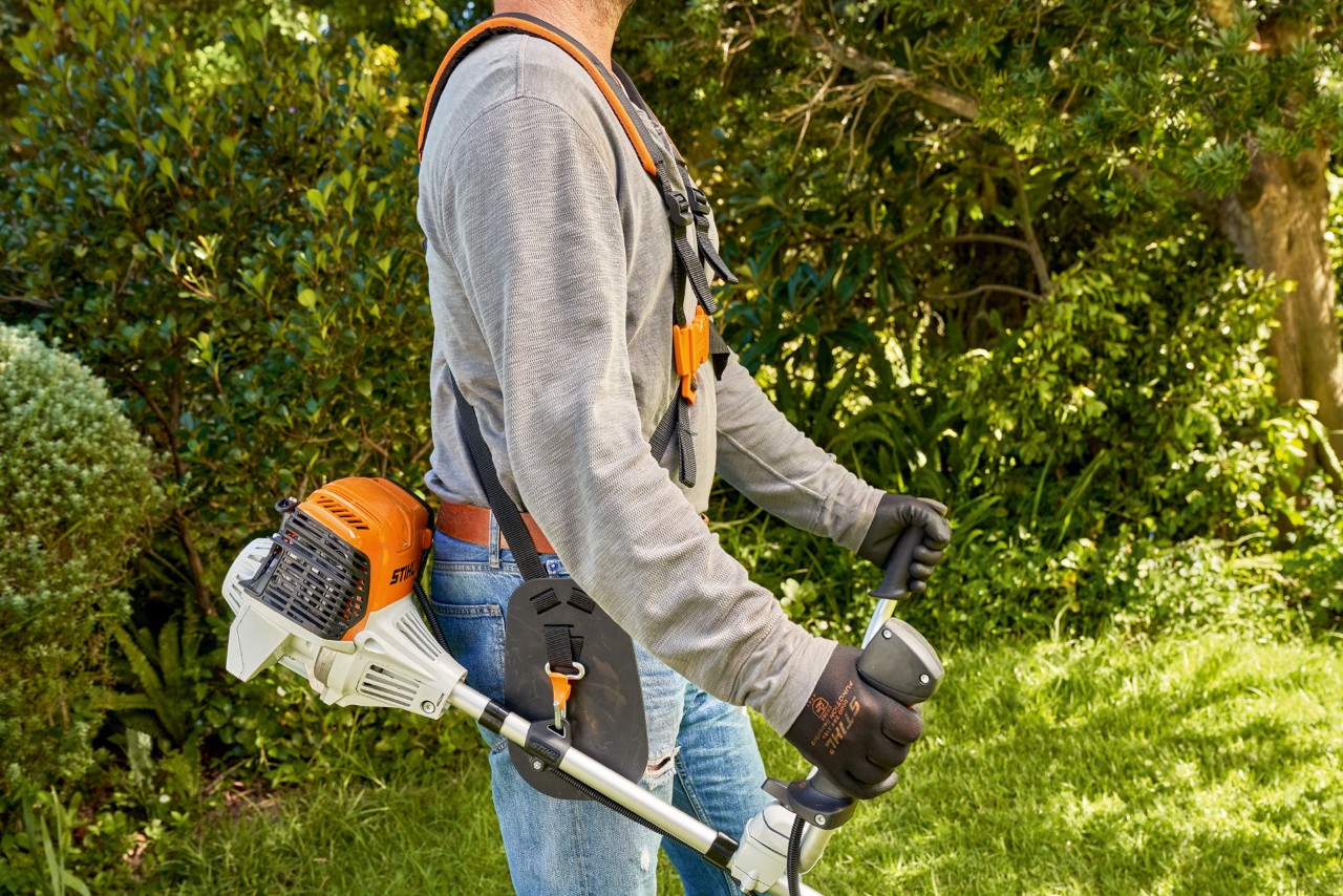 Muž zvedá ze země benzinový křovinořez STIHL FS 91 a začíná sekat 