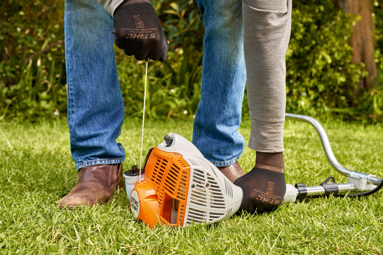 Muž tahá za startovací lanko benzinového vyžínače STIHL FS 56 