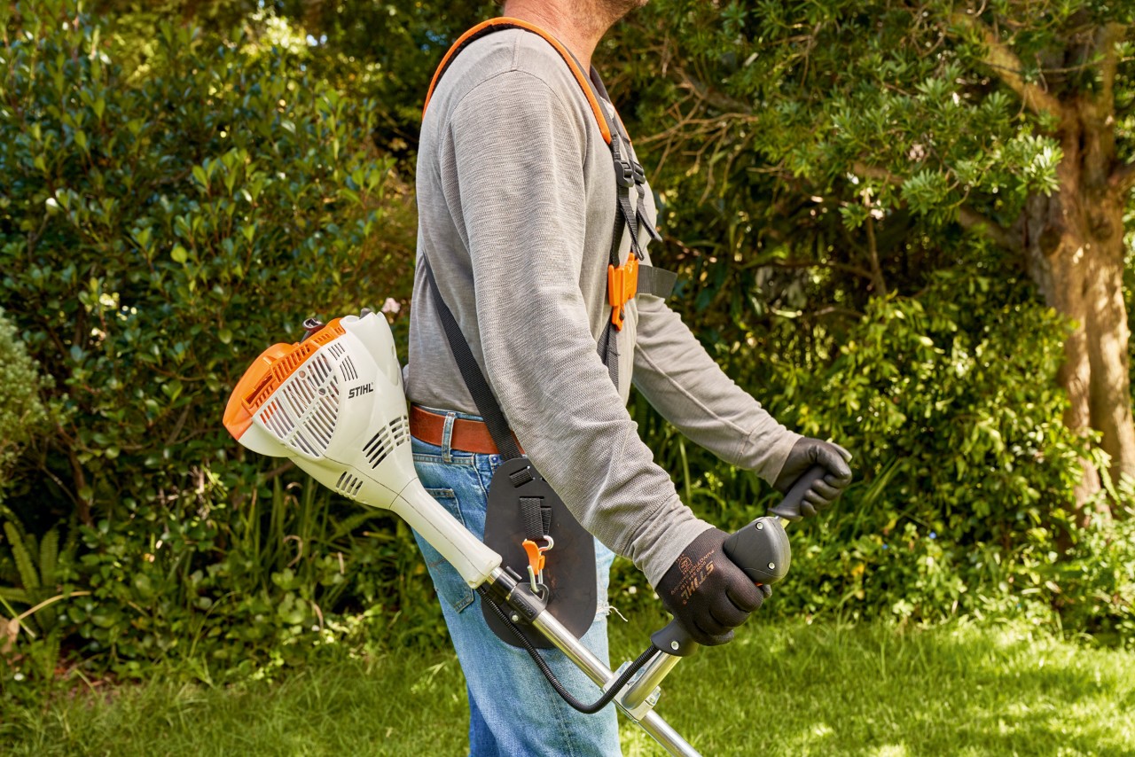 Muž zvedá ze země benzinový vyžínač STIHL FS 56