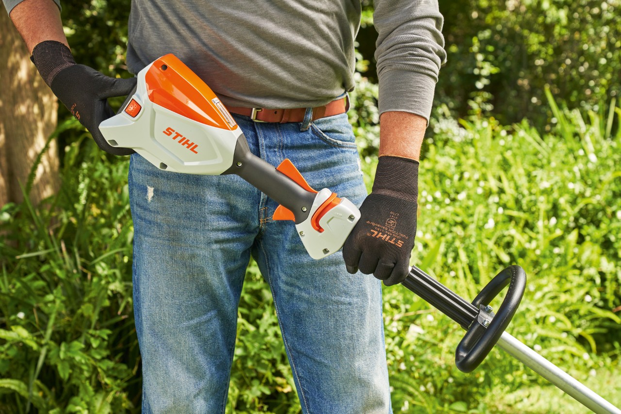 Muž v ochranných rukavicích kontroluje akumulátor vyžínače STIHL FSA 60, aby ho mohl nastartovat