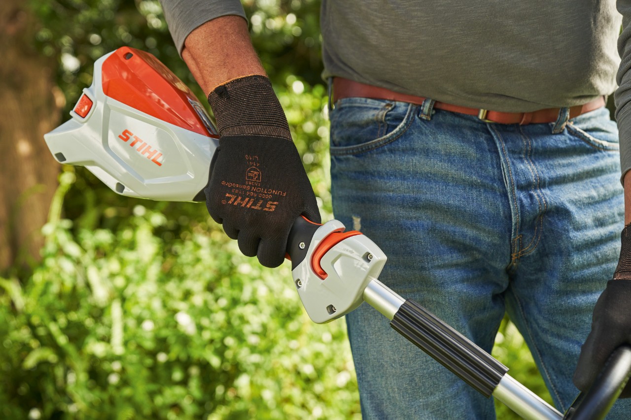Muž v ochranných rukavicích tiskne spínač akumulátorového vyžínače STIHL FSA 60, aby ho nastartoval