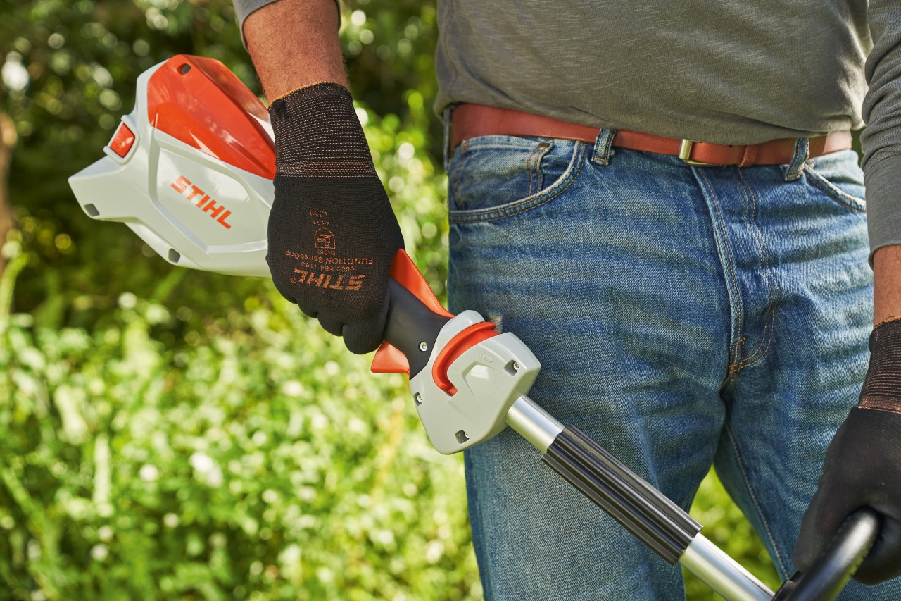 Muž v ochranných rukavicích pouští spínač akumulátorového vyžínače STIHL FSA 60, aby ho vypnul