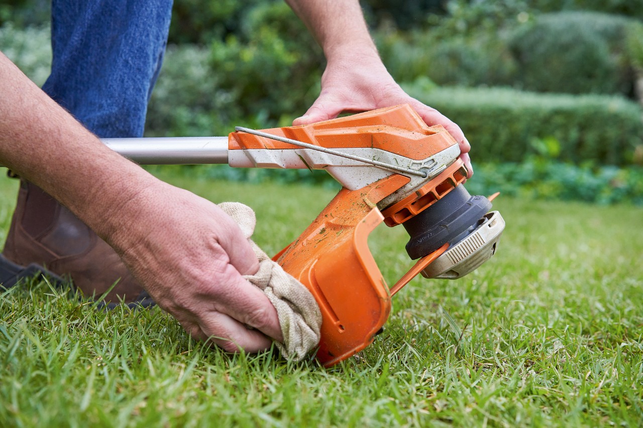 Osoba čistí vlhkým hadříkem kryt vyžínače STIHL