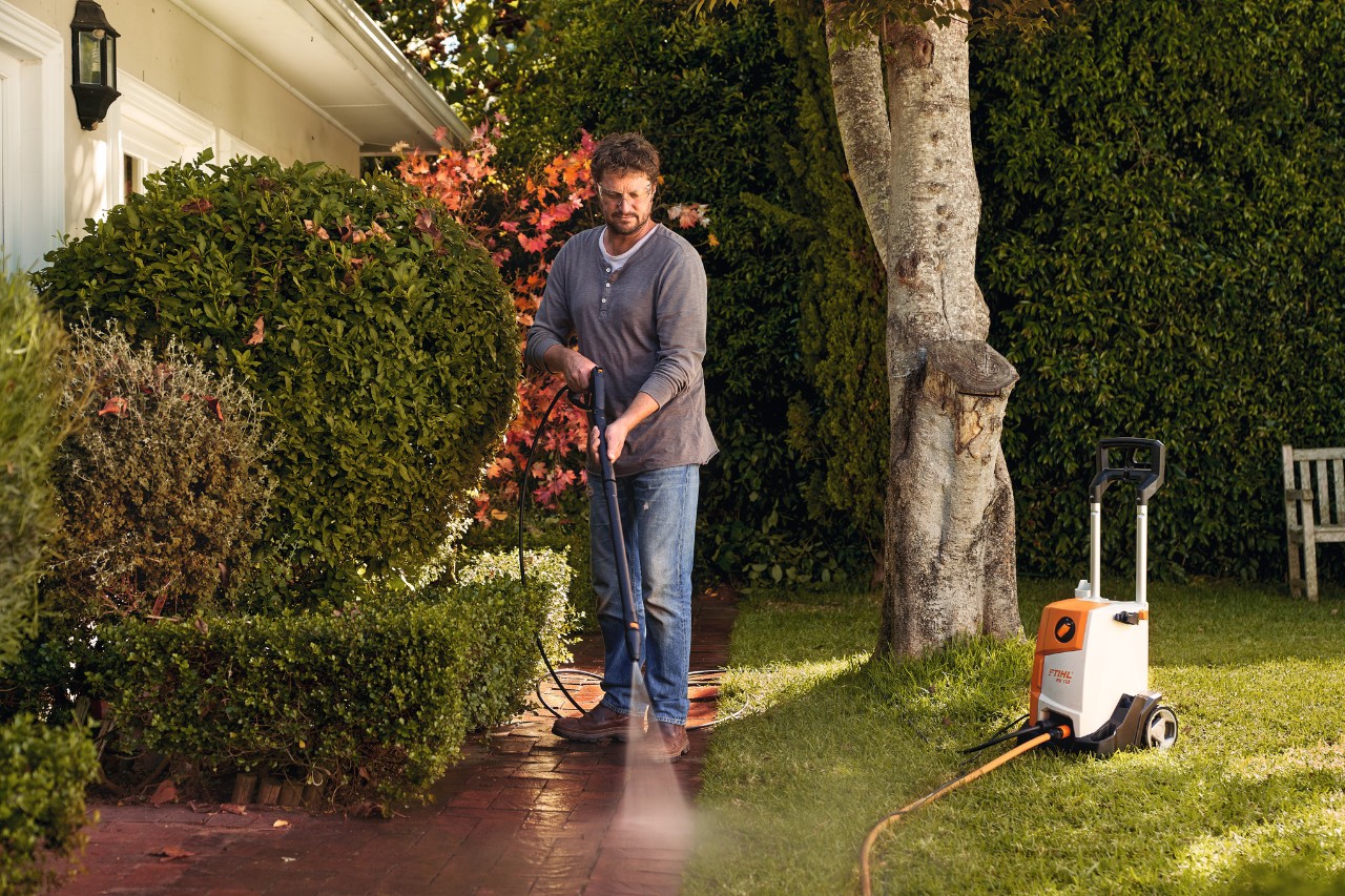 Muž čistí dlažební kostky před svým domem vysokotlakým čističem STIHL RE 110