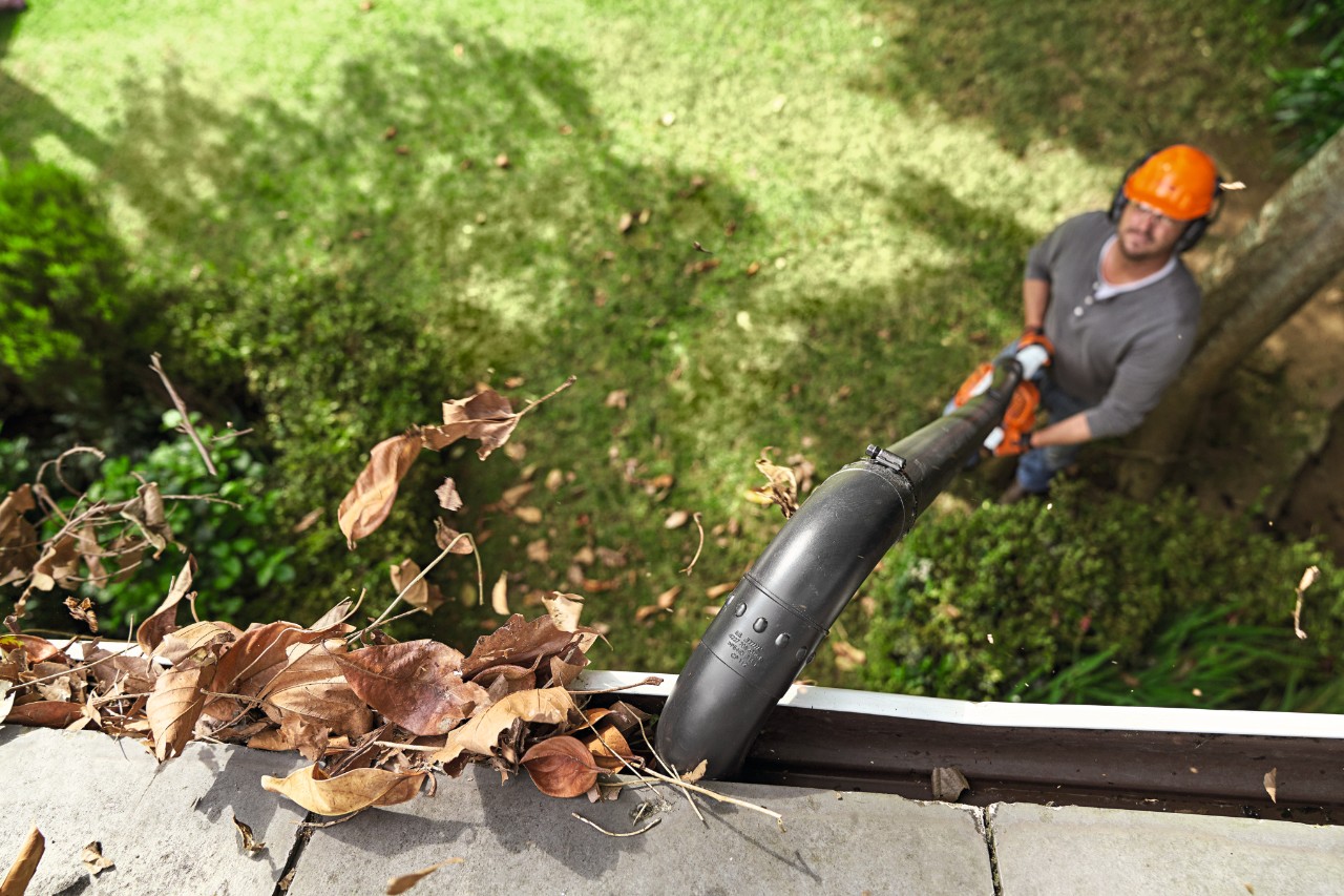 Muž čistí okapní žlaby sadou STIHL na čištění okapních žlabů