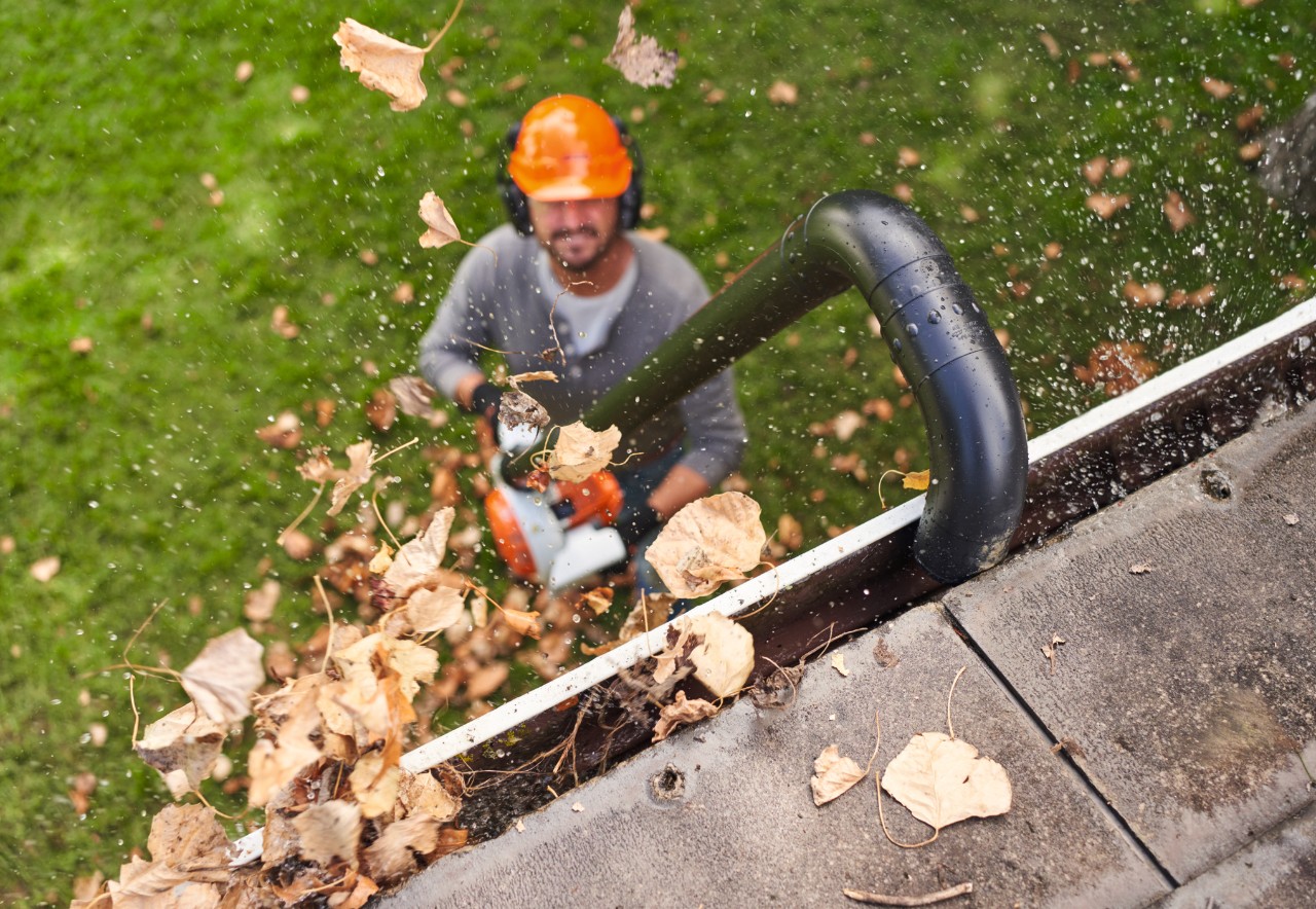 Muž čistí okapový žlab sadou STIHL k čištění okapových žlabů