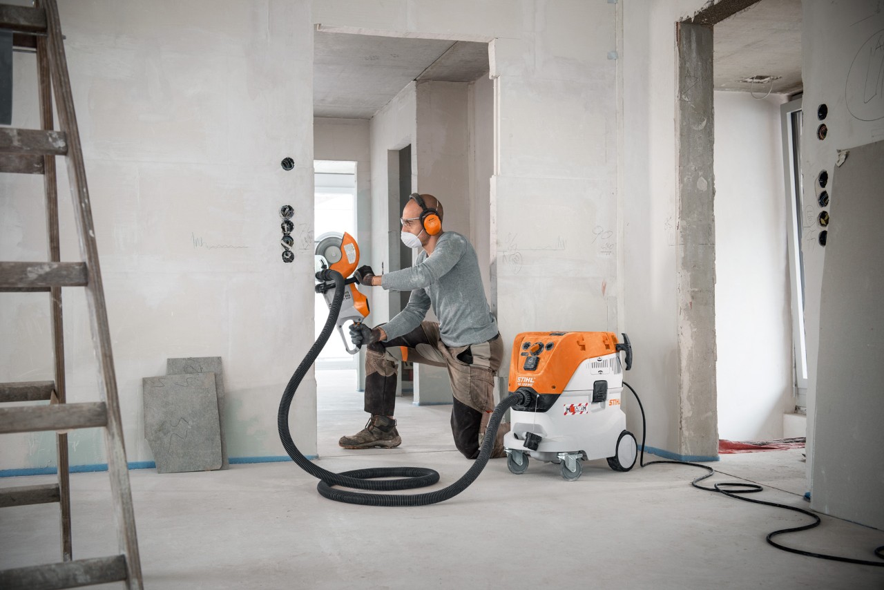 Muž používá vysavač pro mokré a suché čištění STIHL SE 133 ME při práci s rozbrušovacím strojem STIHL TSA 230