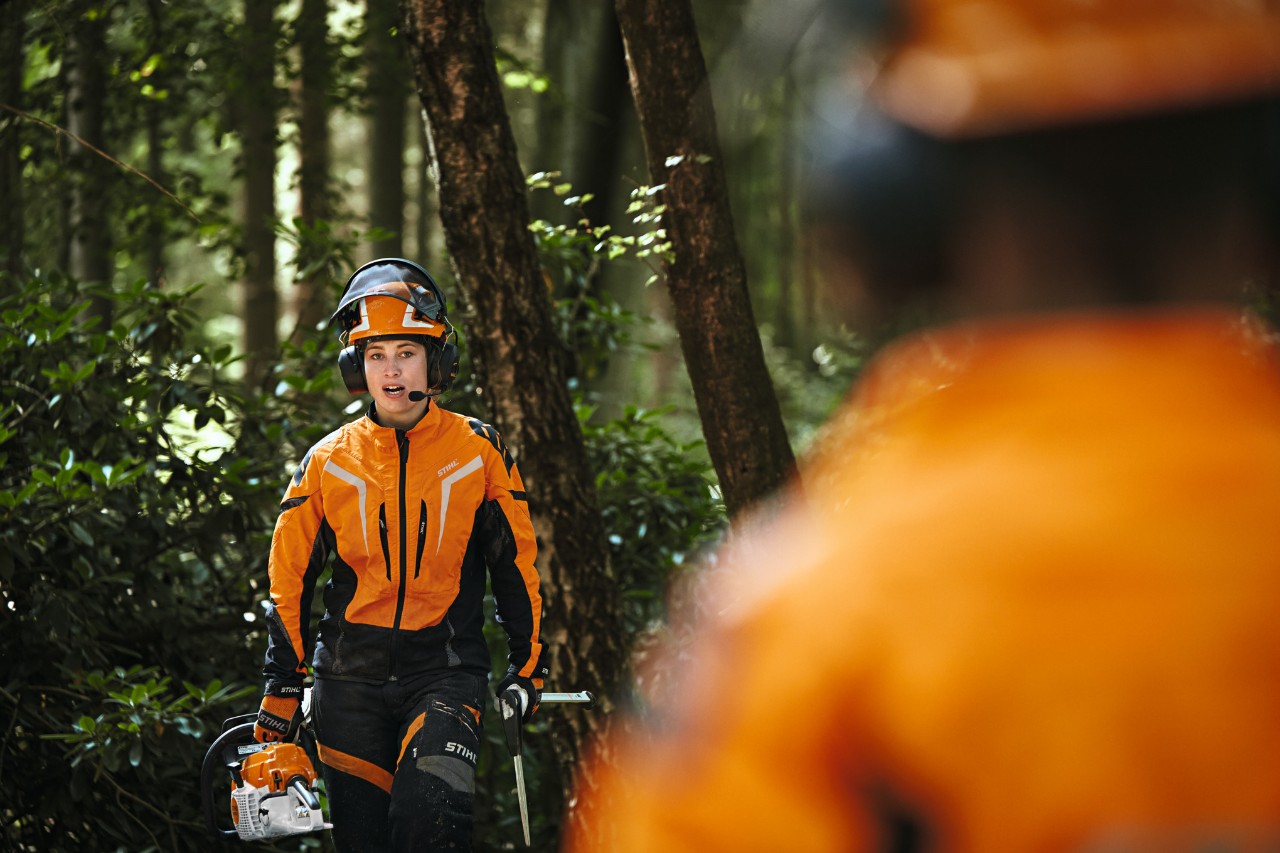 Dva lesní dělníci v ochranném oděvu STIHL s konferenčním systémem STIHL ADVANCE ProCOM 