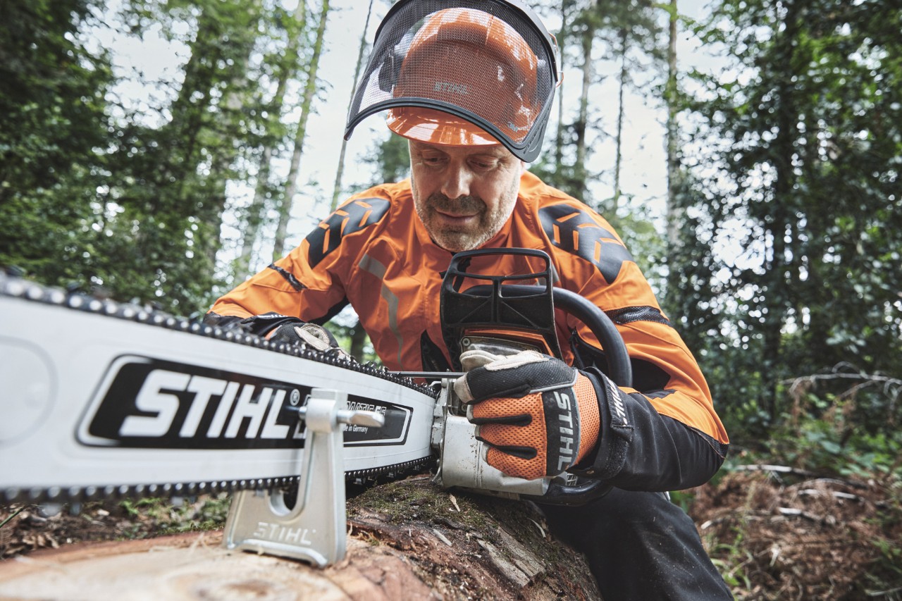 Muž s ochrannými pomůckami pracuje v lese s motorovou pilou STIHL