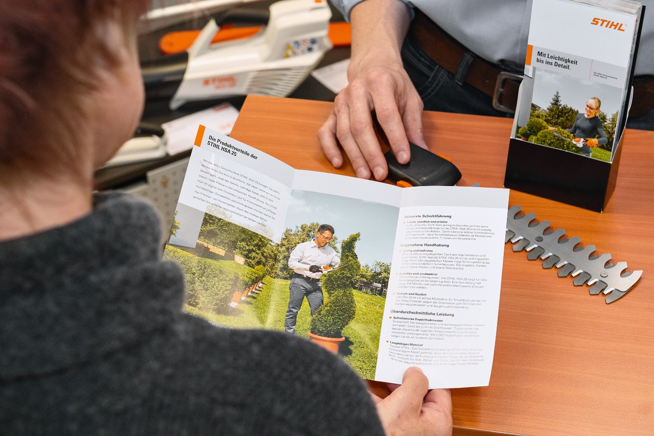 Člověk se v brožuře dívá na výhody výrobku STIHL HSA 25
