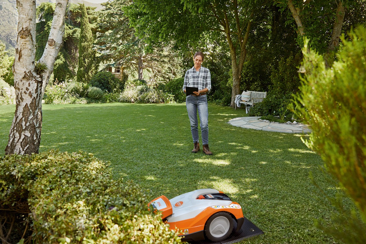 Žena ovládá robotickou sekačku STIHL iMOW® 522 pomocí tabletu