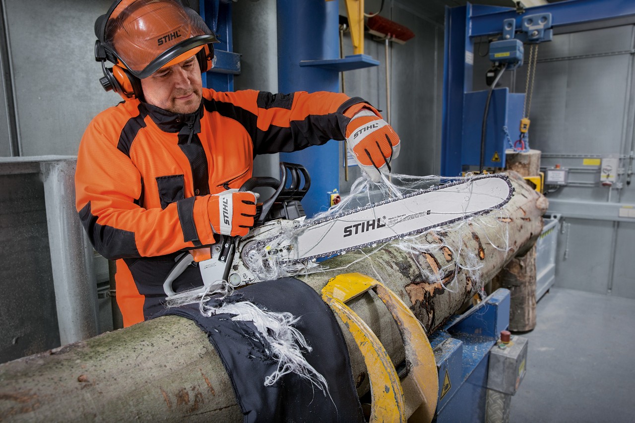 Person in protective clothing tests the cut protection of STIHL protective clothing with a STIHL chain saw
